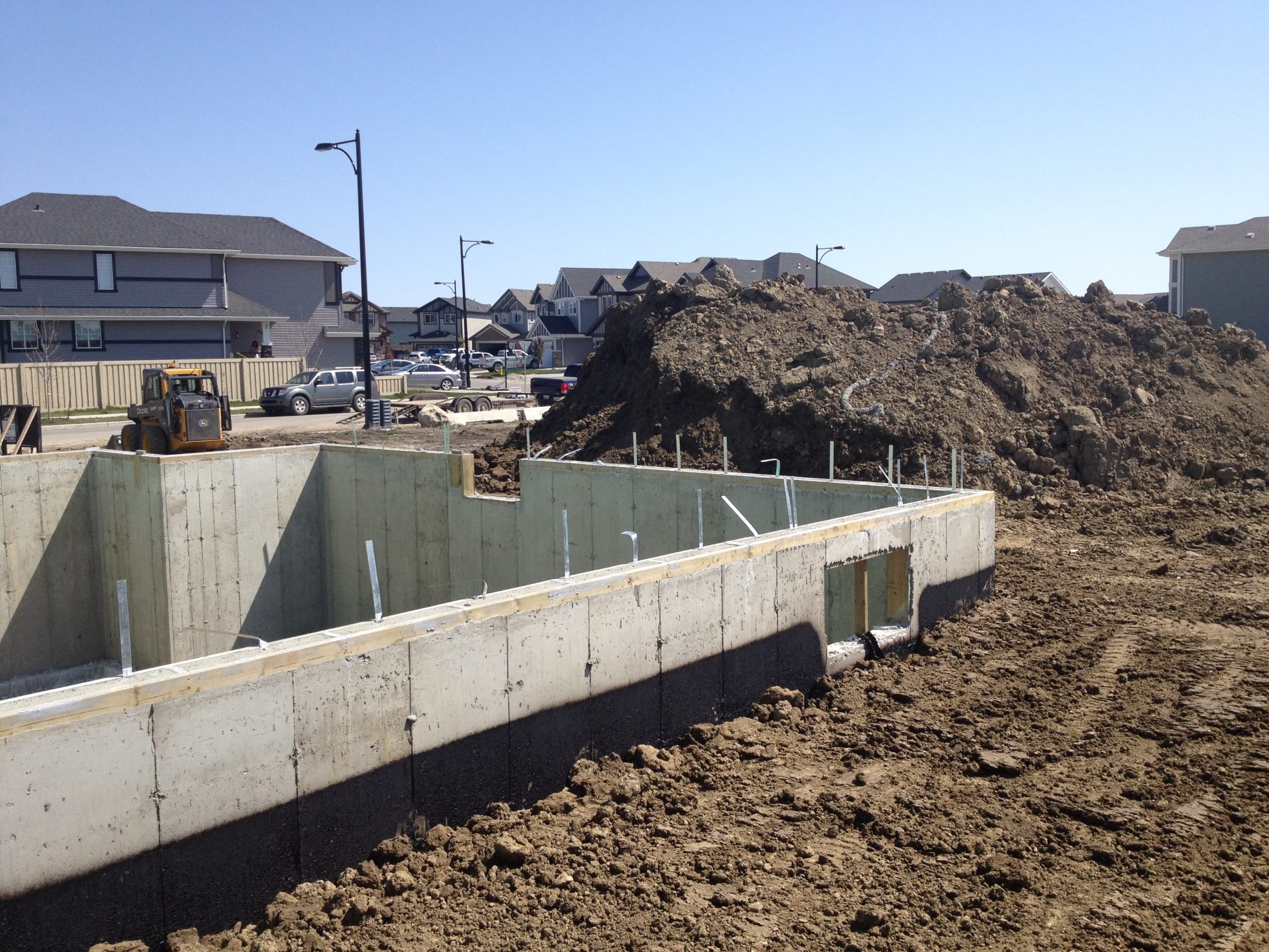 Bobcat Service Near Me excavation of a basement foundation with recent infilling done by bobcat